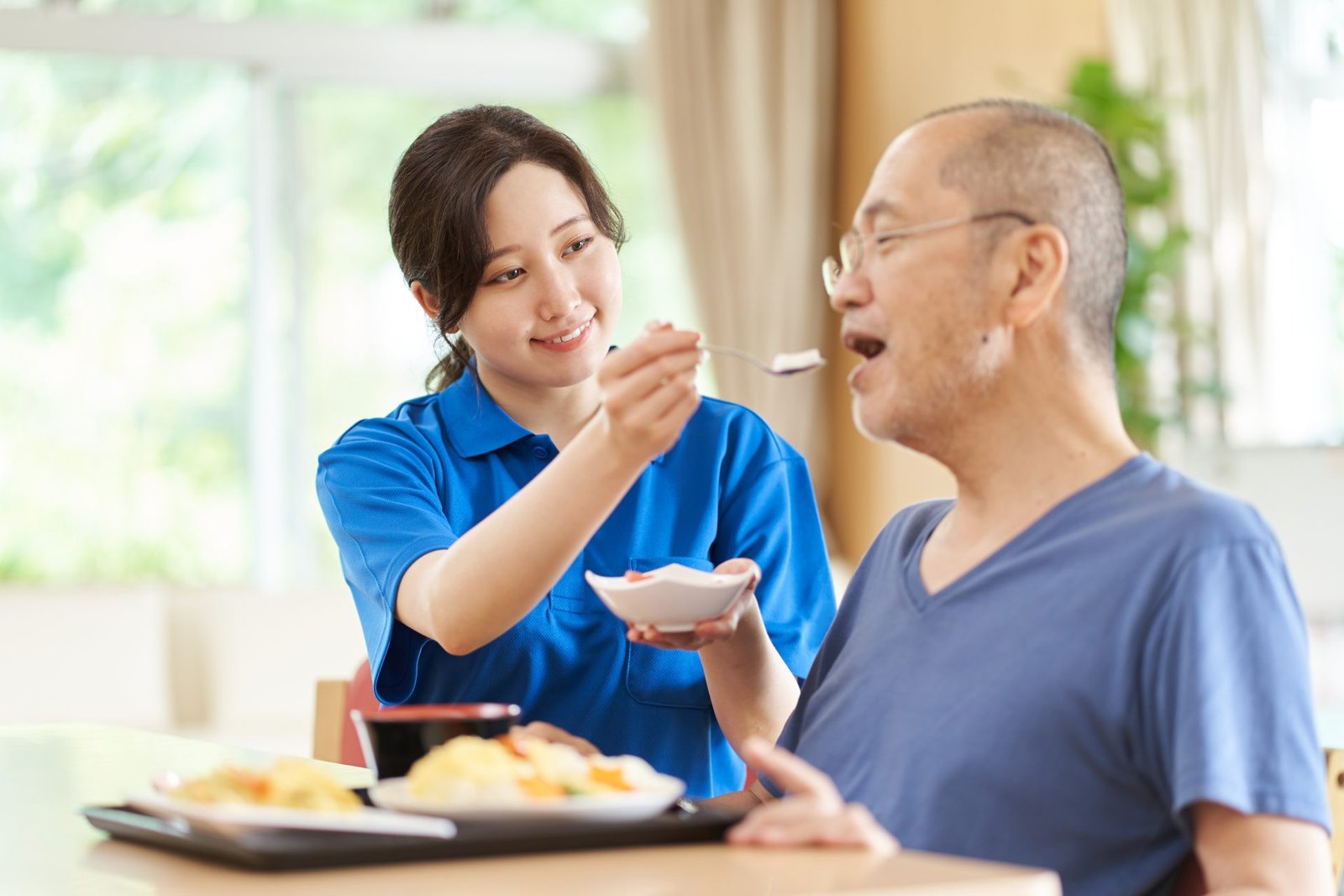 A caregiver who assists the elderly with meals - at Legacy Life Care