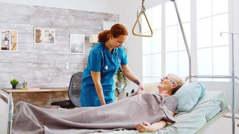 A caregiver assists a woman who is reclining comfortably in a hospital bed, ensuring her well-being and comfort.